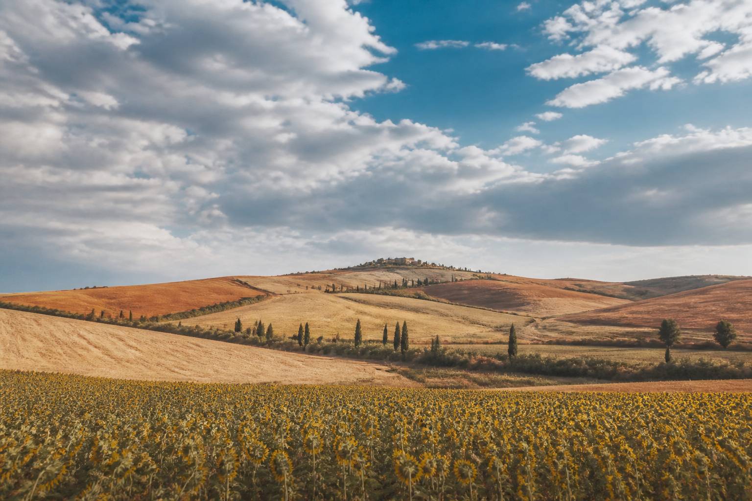 Ciel nuageux au-dessus des collines avec un champ en premier plan