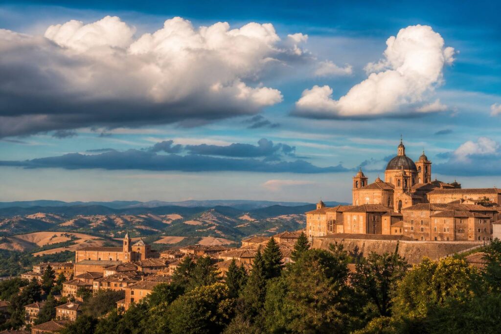 Ville d'Urbino perchée sur sa colline sous un ciel bleu nuageux
