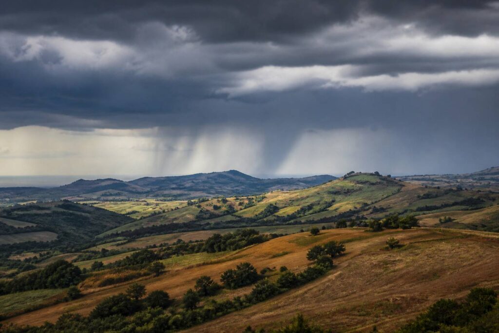 Vallée des Marches sous des nuages d'orage avec rideau de pluie au loin