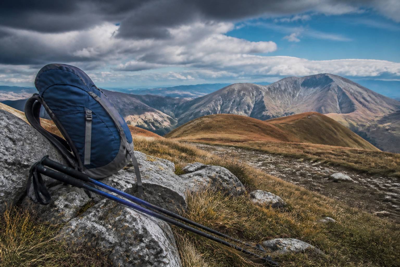 Sac à dos et bâtons posés sur un rocher face aux crêtes du Monte Catria